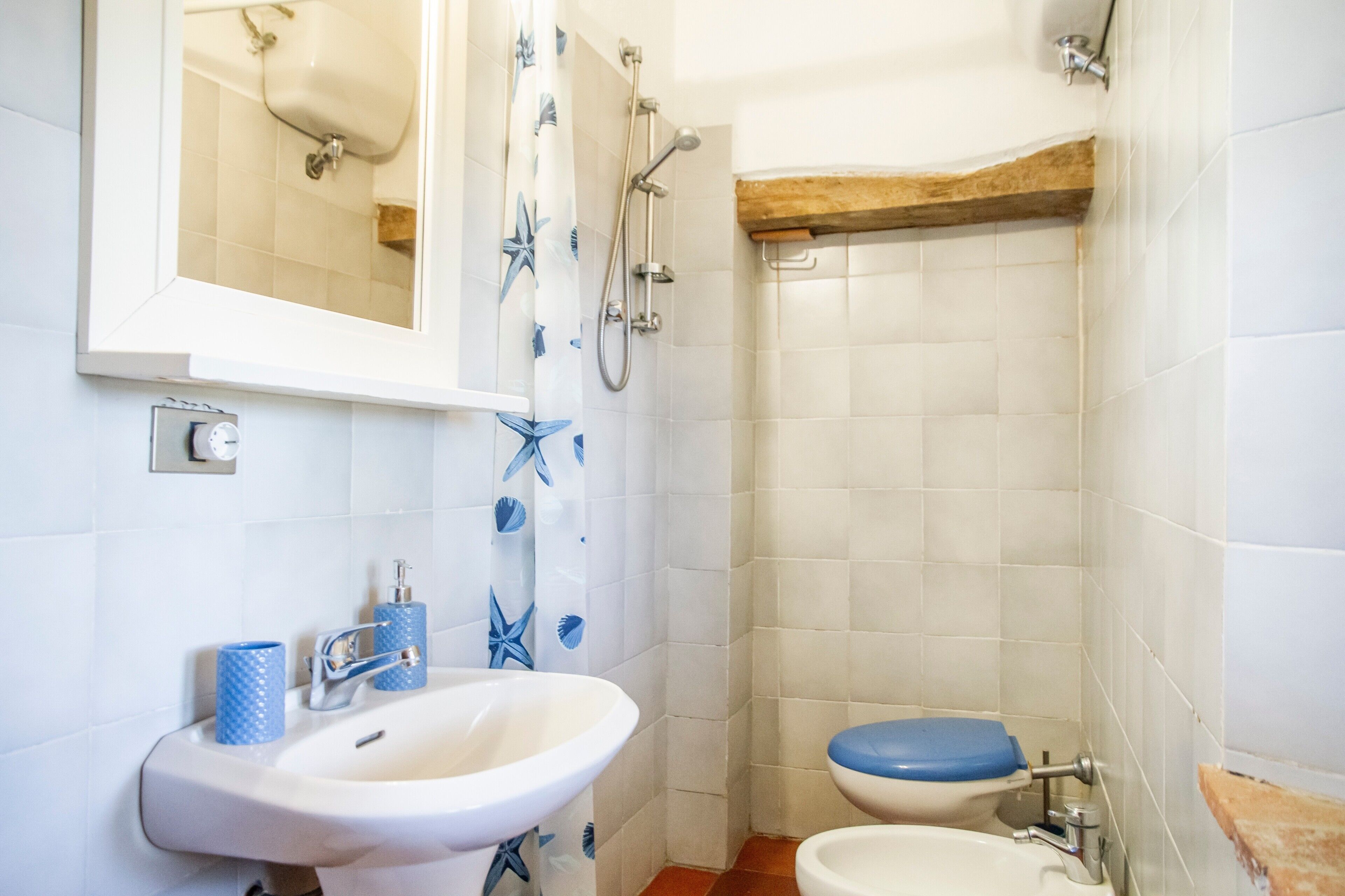 Een badkamer met een wastafel, toilet, douche en spiegel.