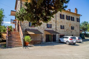Ein Steinhaus mit einer Treppe, zwei Türen und einem weißen Auto.