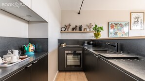 A modern kitchen with a built-in oven, a sink, and a countertop with a kettle and teapot.
