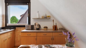 A kitchen with a window, a countertop, and a view of a house. - Apartment 'Gundlach' with Shared Terrace, Shared Garden and Wi-Fi (Hessisch Lichtenau)