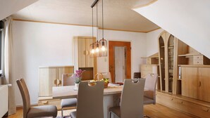 A modern kitchen with wooden cabinets, a dining area with chairs, and a hanging light fixture. - Apartment 'Gundlach' with Shared Terrace, Shared Garden and Wi-Fi (Hessisch Lichtenau)