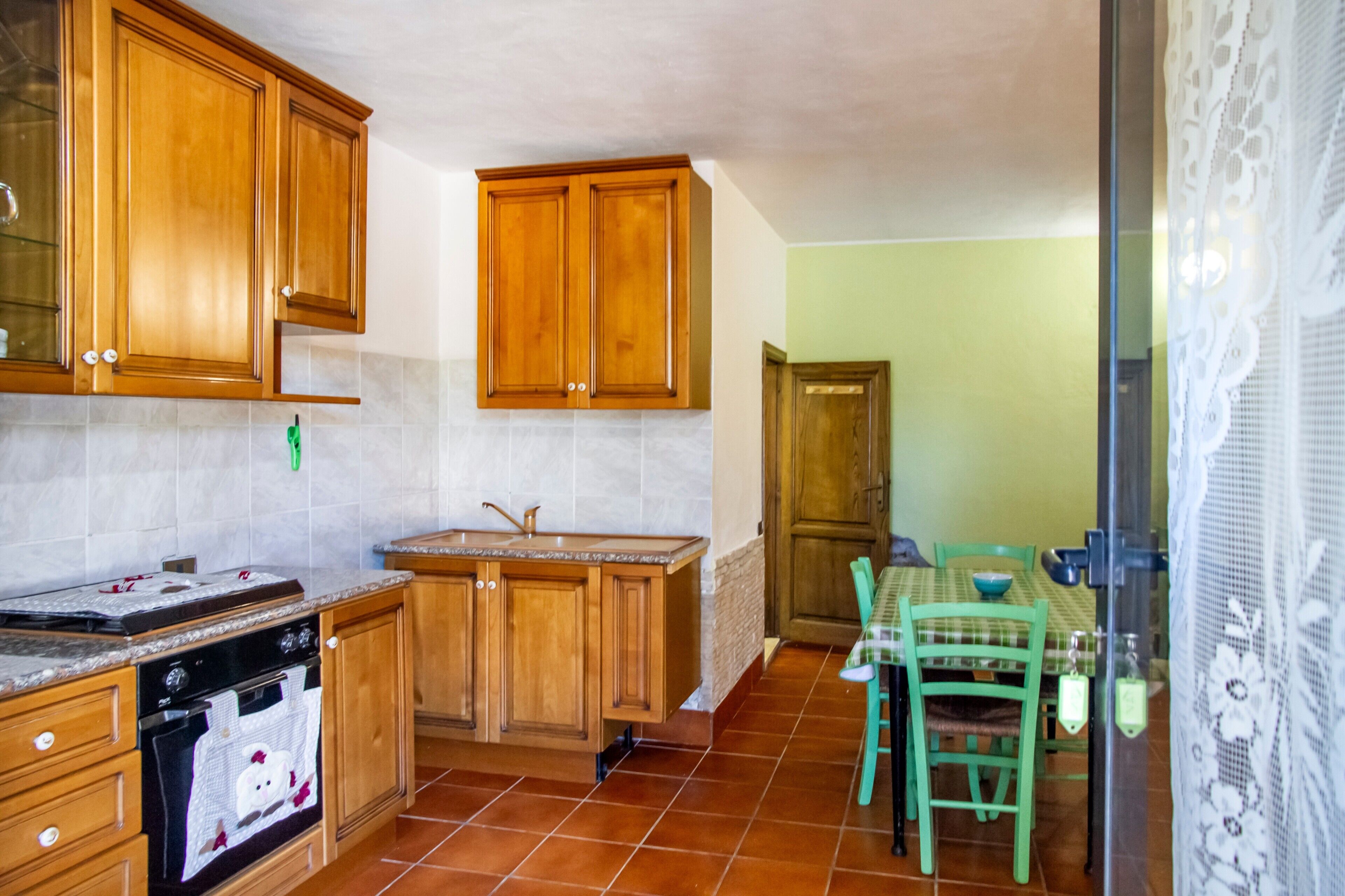Une cuisine avec des meubles de rangement en bois, un plan de travail, un évier et un coin repas comprenant une table et des chaises.