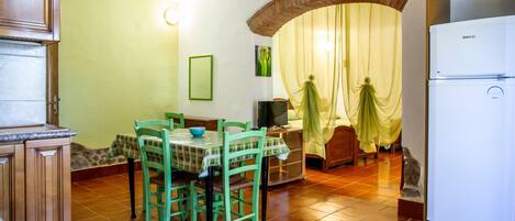 A kitchen with a dining table, chairs, a refrigerator, and a TV.