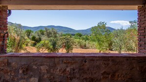 A view through a window with a stone wall and brick ledge, overlooking a landscape with trees and distant hills. - Apartment 'Taverna' with Private Terrace, Shared Garden and Wi-Fi (Gavorrano)