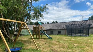 Une aire de jeux avec des balançoires, un toboggan et une structure d’escalade.
