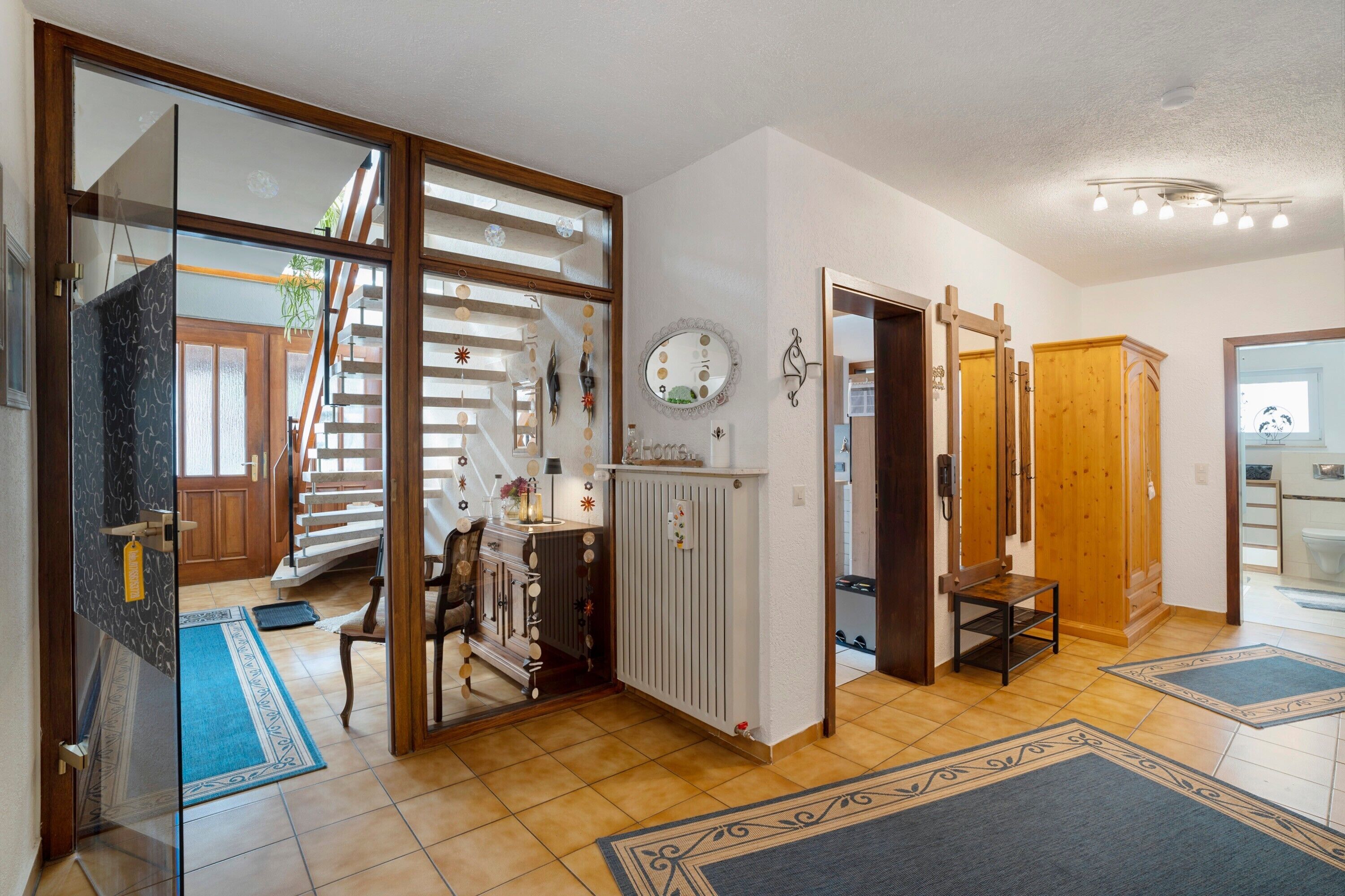 Ein geräumiger Flur mit einer Holztreppe, einem Spiegel und einem Holzschrank.