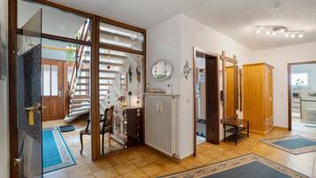 Ein geräumiger Flur mit einer Holztreppe, einem Spiegel und einem Holzschrank.