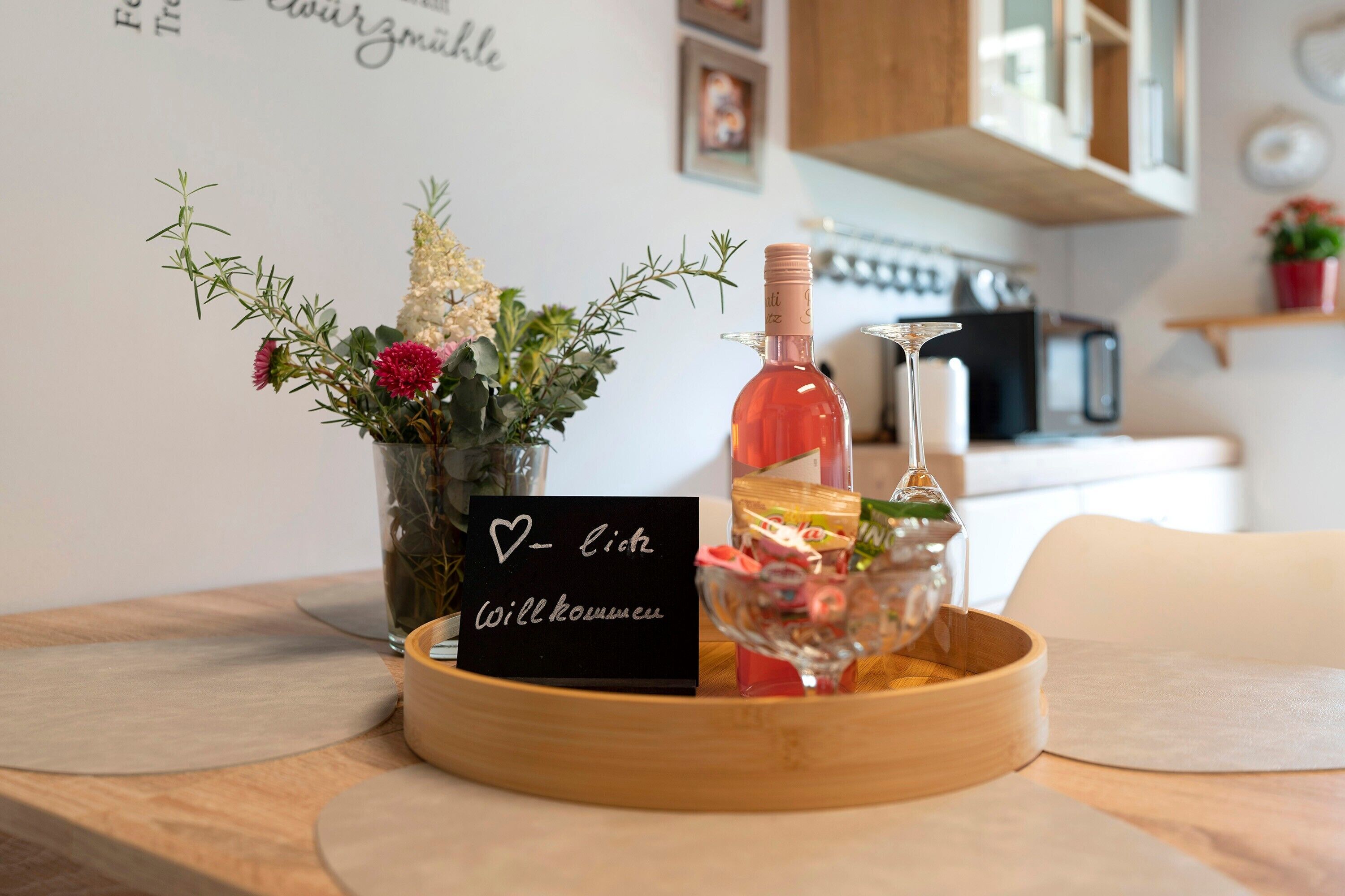 A wooden tray with a bottle of rosé wine, a glass, and a card with a heart symbol and text.