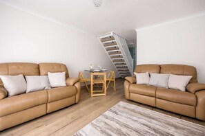 Un salon avec deux canapés en cuir, une table basse en bois et un escalier.