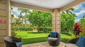 A covered outdoor seating area with wicker furniture and a view of a well-maintained garden. - Summer Deal Ground Floor 3BR Poipu Condo with Pool Beach Access (Koloa)