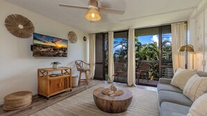A spacious living area with a wooden coffee table, a sofa, and a television mounted on the wall.