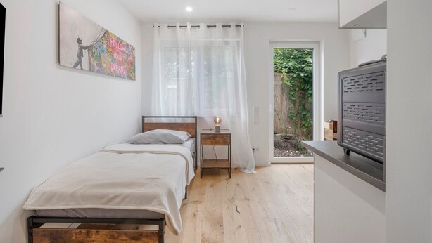 Een slaapkamer met een bed, nachtkastje en een schilderij aan de muur.