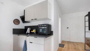 Een kleine keuken met een inbouwoven, een klok en een handdoek aan de deur.