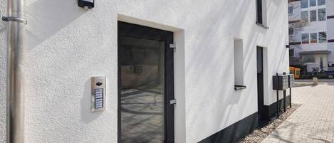 A building with a white exterior, a black-framed door, and a small window.