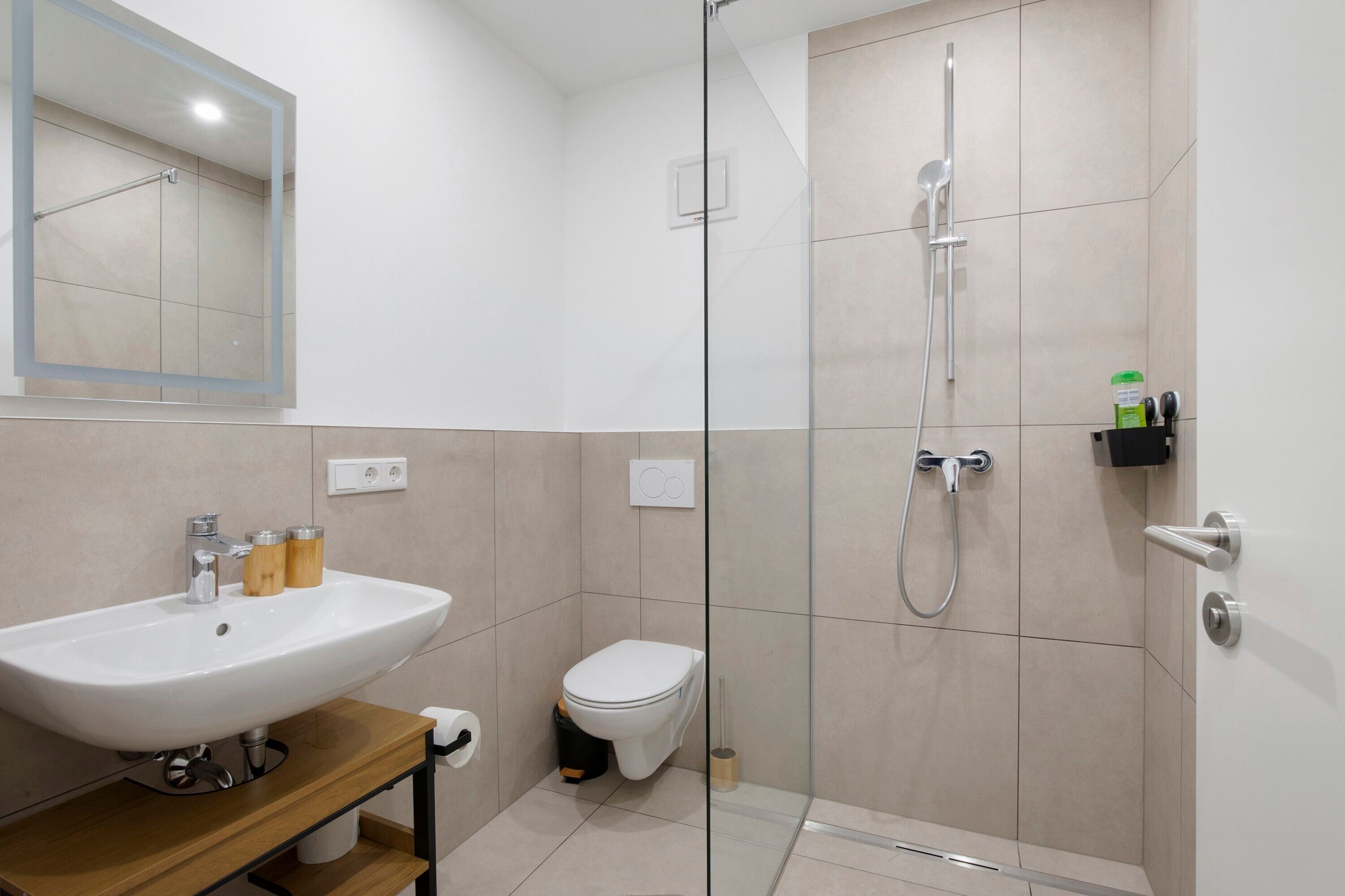 A modern bathroom with a glass-enclosed shower, a white sink, and a toilet.
