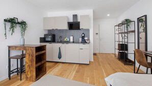 Een moderne keuken met witte kasten, een magnetron en een hangplant.