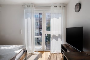 Une chambre avec un lit, une télévision et une porte-fenêtre coulissante donnant sur un balcon.