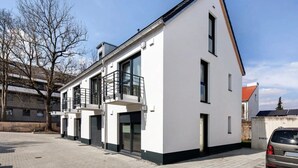 Een modern woongebouw met twee verdiepingen, een balkon, een garage en een verharde oprit.