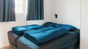 Ein Bett mit blauer Bettwäsche und einem Fenster mit Vorhängen.