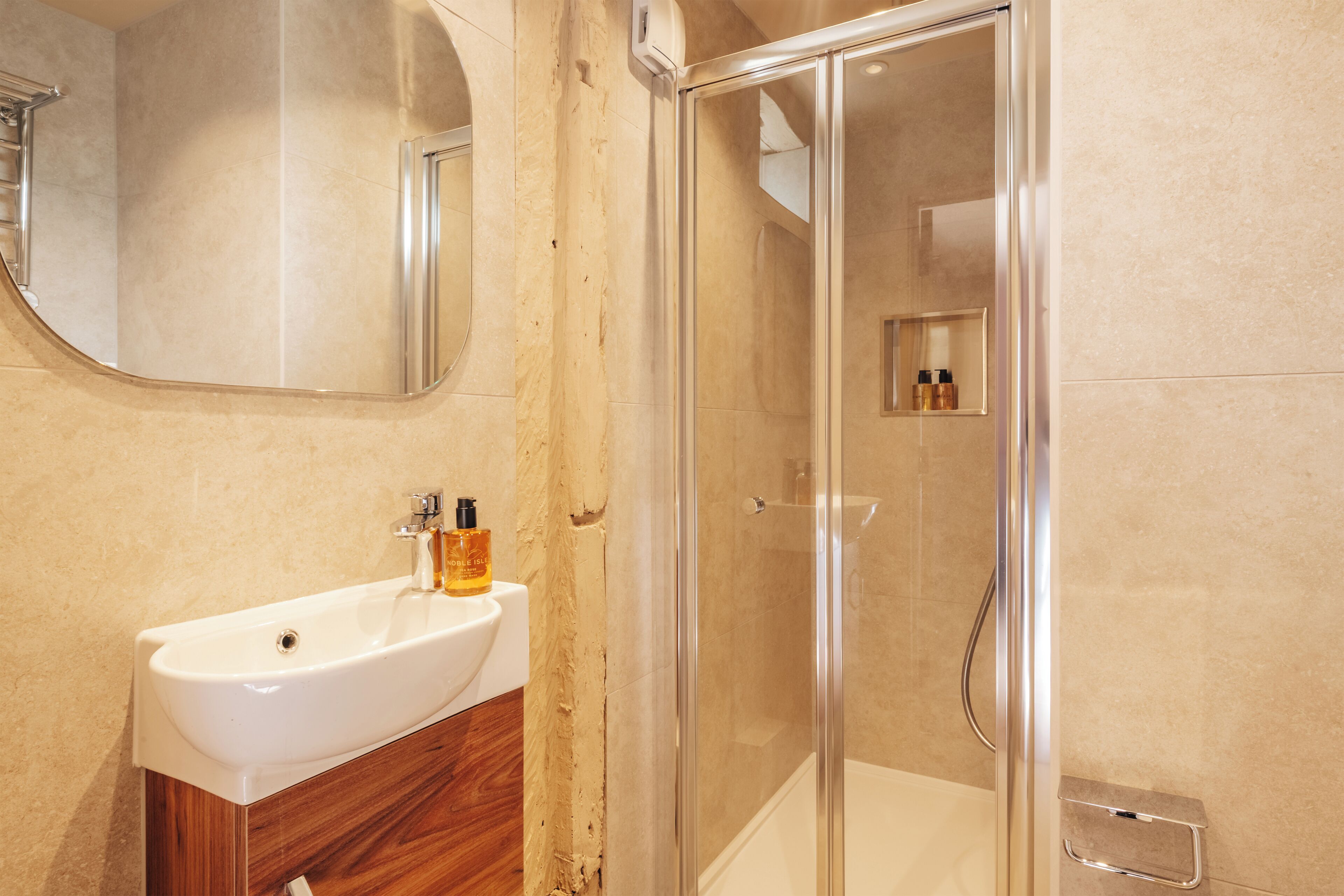 A bathroom with a white sink, wooden vanity, and a glass-enclosed shower.