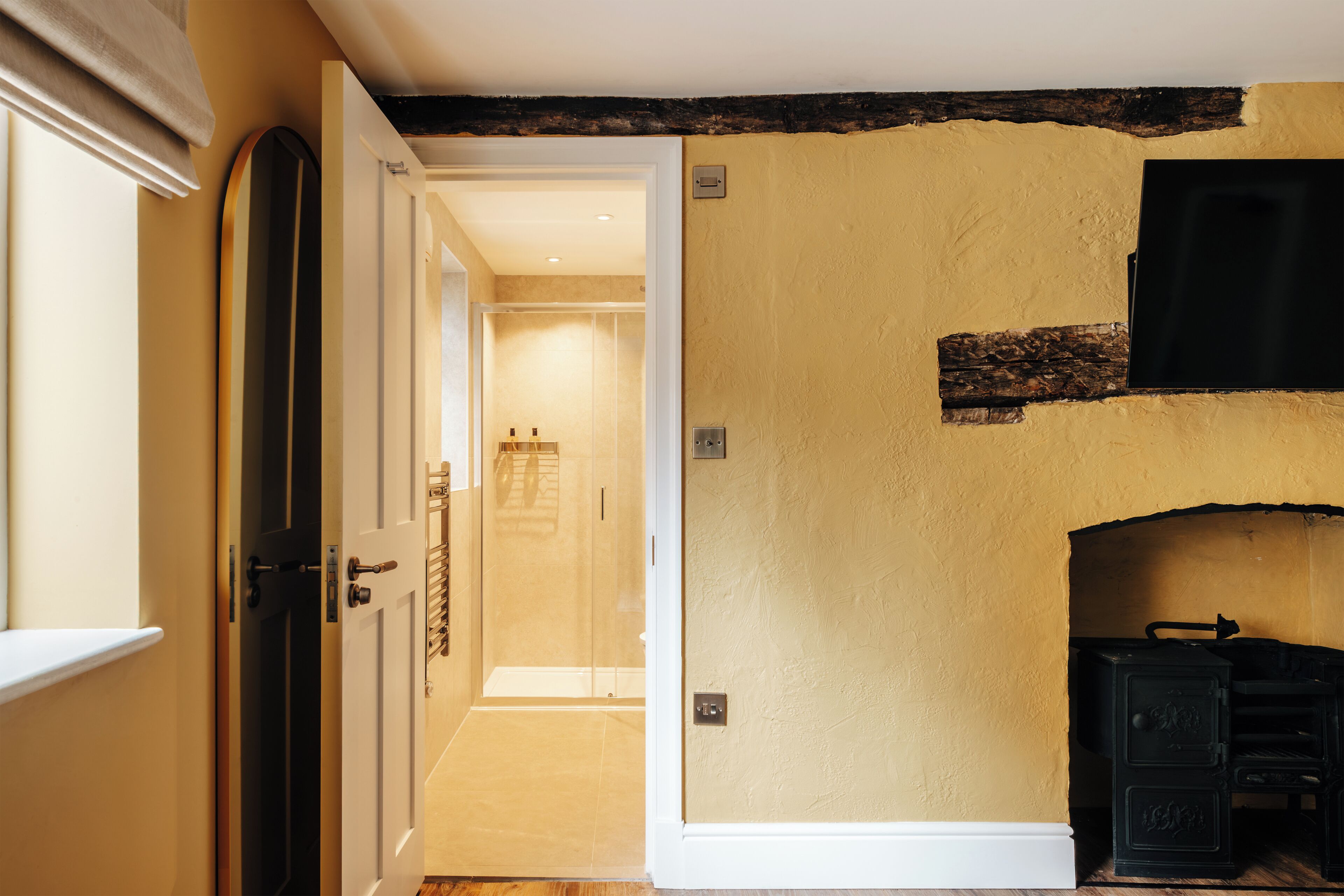A hallway with a wooden door, a fireplace, and a tiled floor.
