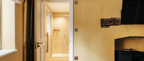 A hallway with a wooden door, a fireplace, and a tiled floor.