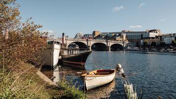 A river with boats docked, a bridge, and buildings in the background.