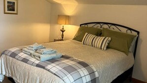 A neatly made bed with a checkered bedspread, a lamp on the nightstand, and a framed picture on the wall.