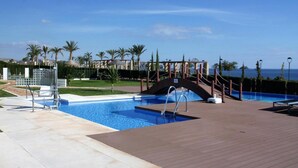 A pool area with a wooden deck, a bridge, and a view of the sea. - Lorandalou - Two Bedroom Apartment, Sleeps 4 (San Juan de los Terreros)
