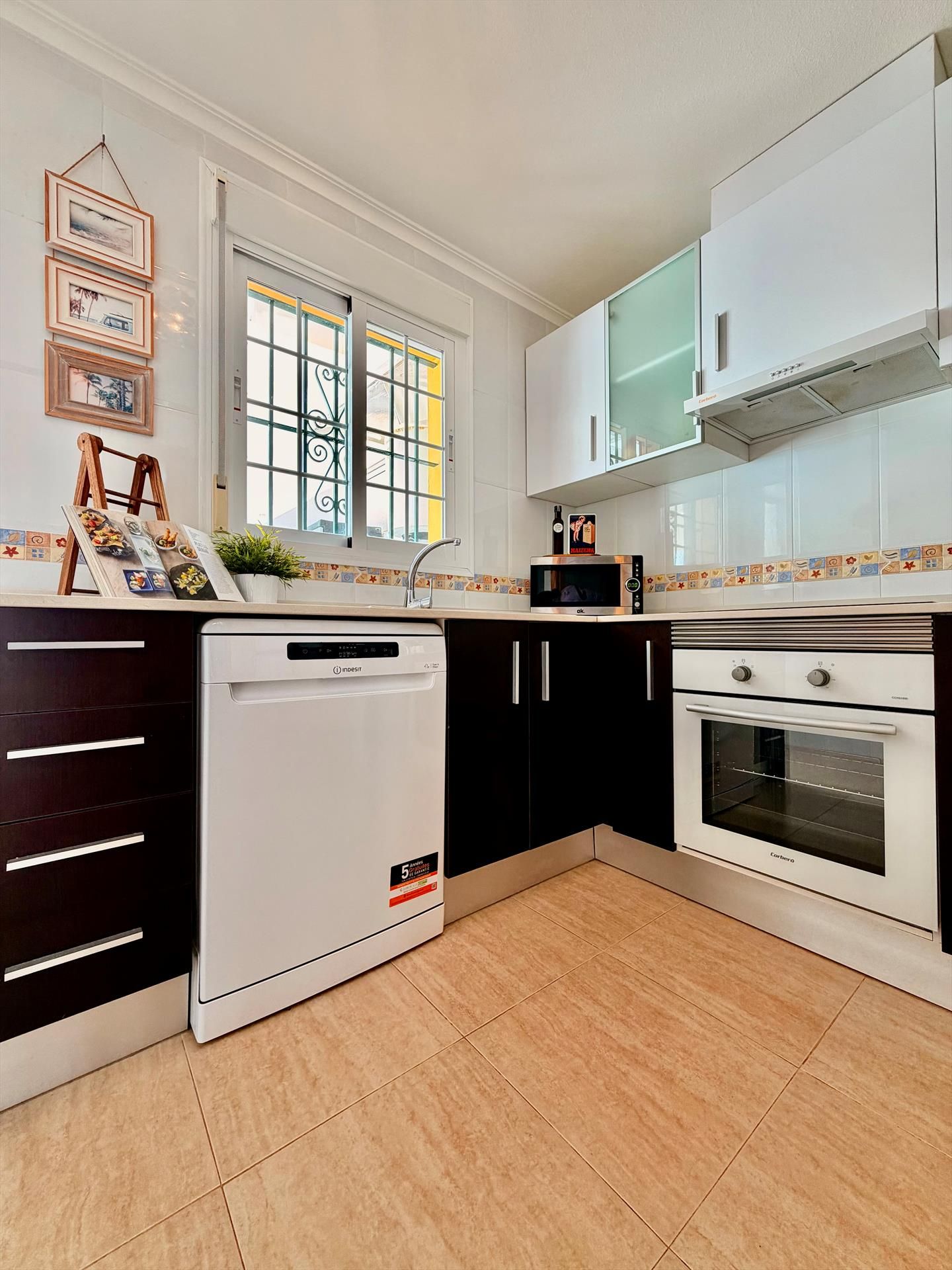 A kitchen with a dishwasher, oven, microwave, and cabinets.