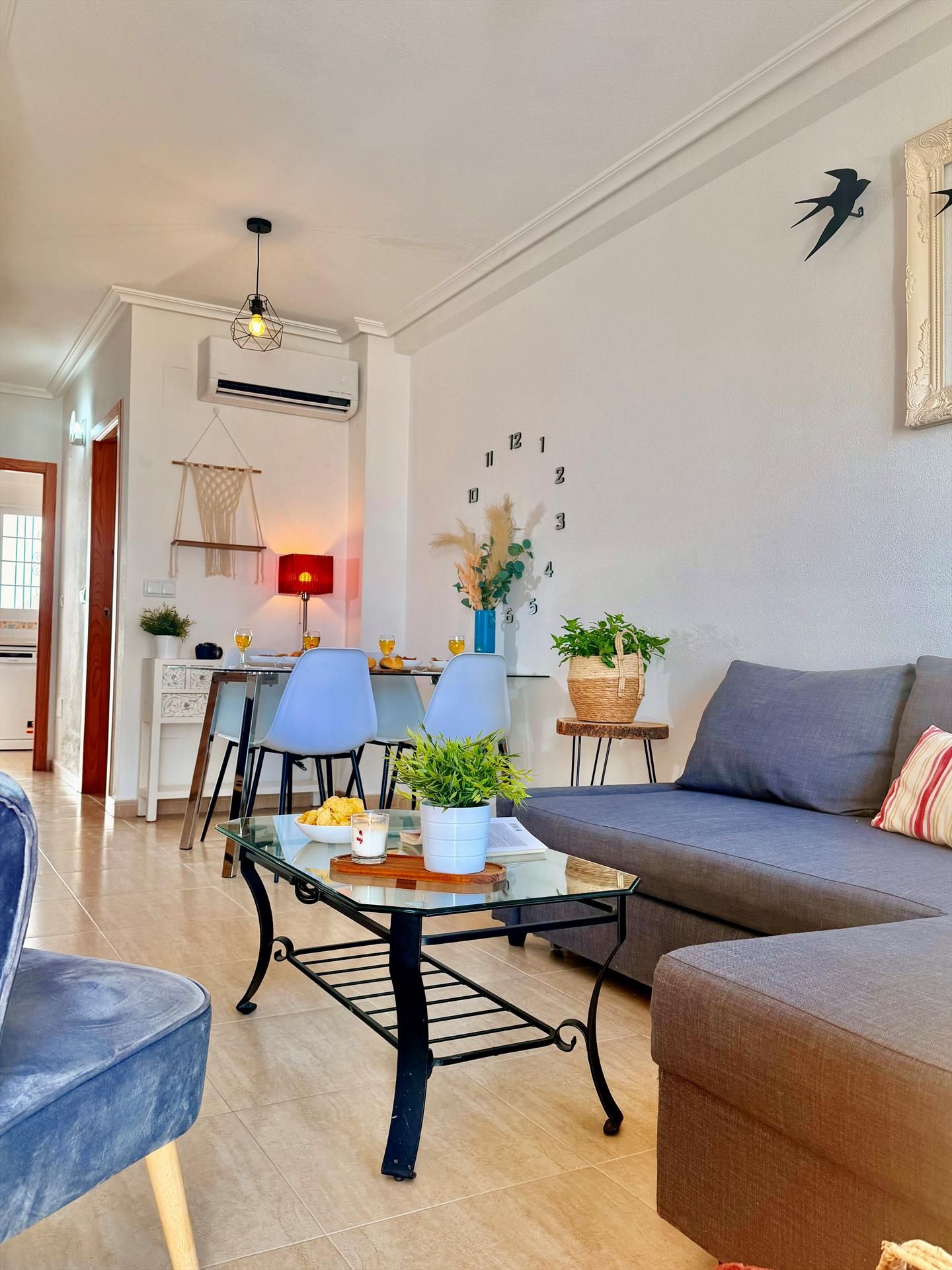 A modern living room with a sofa, chairs, a coffee table, and a dining area with a lamp.