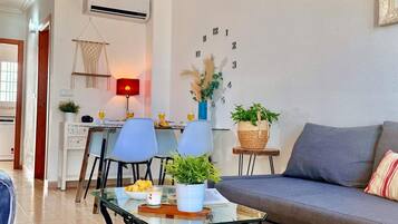 A modern living room with a sofa, chairs, a coffee table, and a dining area with a lamp.