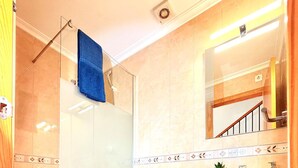 Une salle de bain avec une douche à parois de verre, des toilettes, un lavabo et une serviette bleue sur le sol.