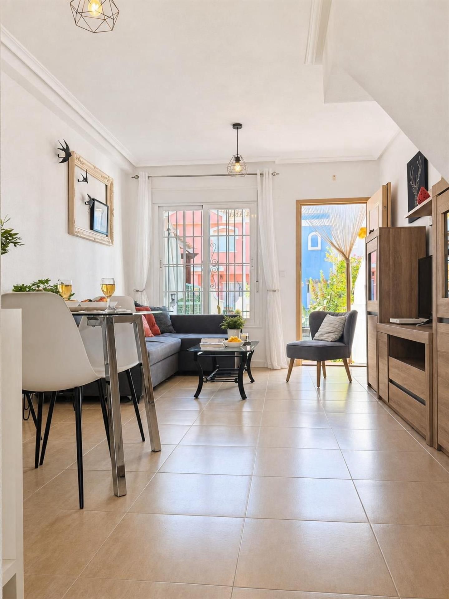Una sala de estar moderna con comedor, un sofá, una mesa de centro y un mueble para televisión.
