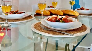 Une table à manger avec des assiettes remplies de nourriture, des verres de vin et un vase décoratif contenant des plumes d’herbe des pampas.