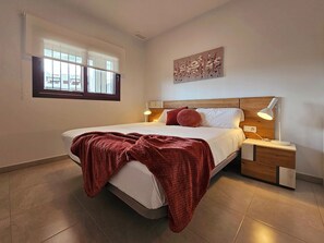 A bedroom with a bed, nightstands, a window, and a wall-mounted artwork.