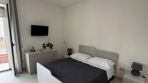 A modern bedroom with a bed, bedside tables, a TV, and a sliding door.