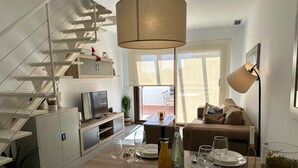 A modern kitchen with a dining area, a staircase, and a living room with a sofa and a TV. - Casa Pedro - Two Bedroom Apartment, Sleeps 4 (San Juan de los Terreros)
