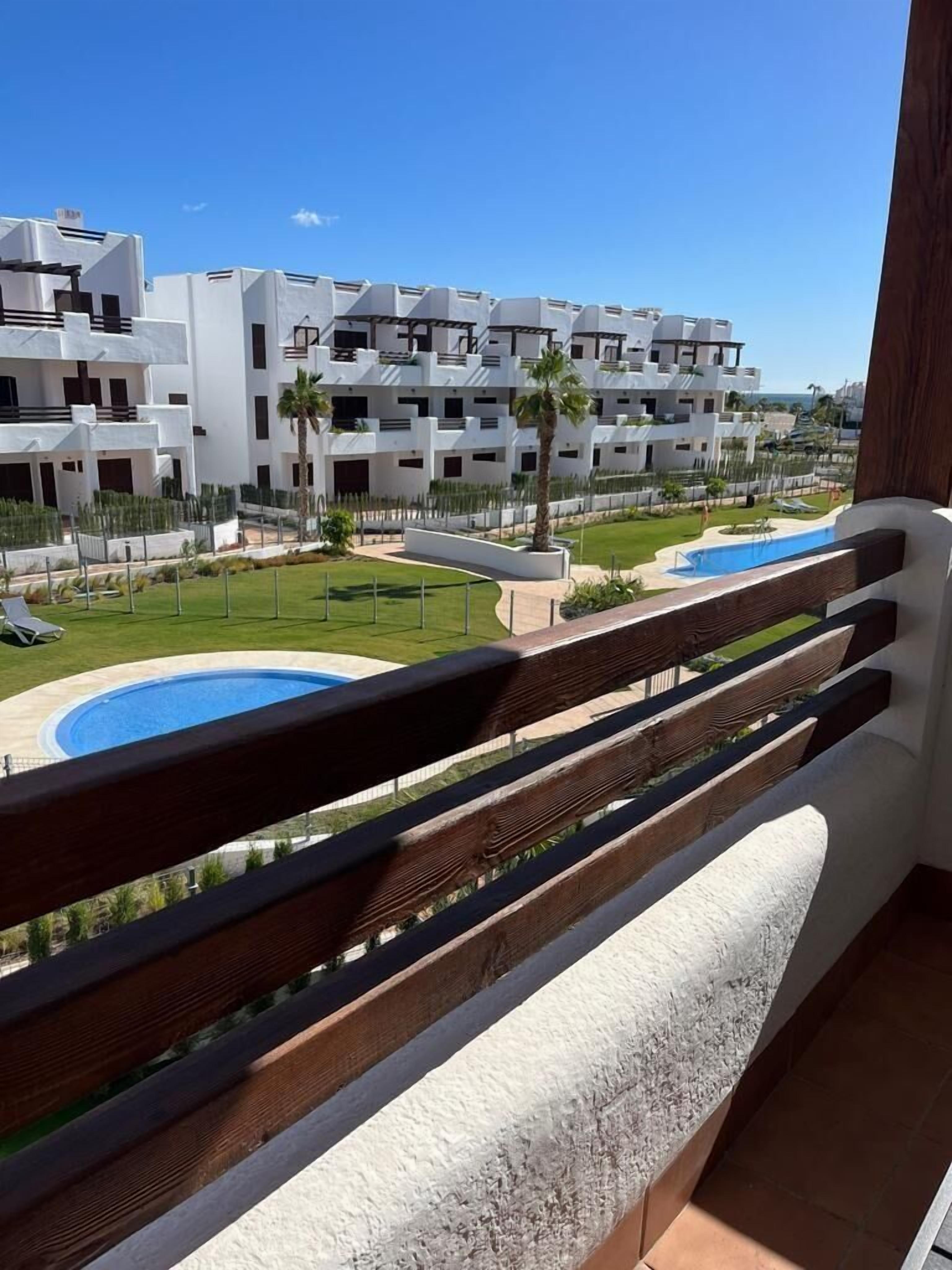 Un balcón con vistas a una piscina y un complejo residencial.