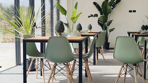 A modern dining area with tables and chairs, large windows, and indoor plants. - Villa Principi di Moschitta - luxury stay in Sicily and event space (Caltagirone)