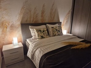 Un dormitorio con cama, dos mesitas de noche y una pared con textura.