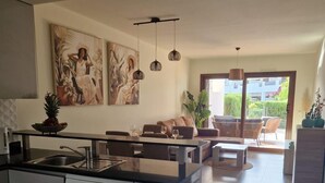 Cocina moderna con lavavajillas, comedor con sofá y vista al exterior.