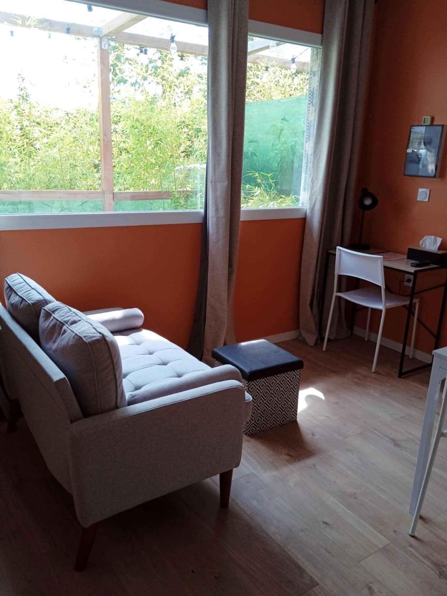 Une pièce comprenant un canapé, un bureau, une chaise et une fenêtre avec des rideaux.
