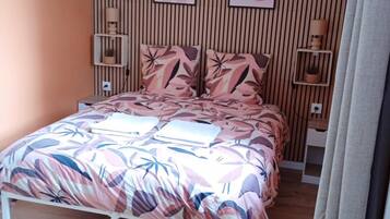 Un dormitorio con una cama, un revestimiento de madera en la pared y dos estantes fijos a la pared con lámparas.