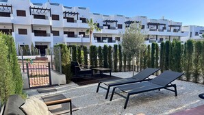 Une terrasse sur le toit, aménagée avec des chaises longues, une table et un petit coin salon.