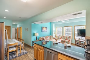 A kitchen with a central island, wooden cabinets, and a dining area with chairs and a table.