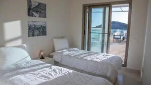 A bedroom with two beds, a nightstand, and a large sliding glass door leading to a balcony. - Casa Sierra Golf - Two Bedroom Apartment, Sleeps 4 (Pulpí)