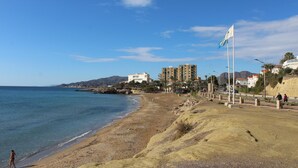 Una playa con una bandera, edificios y un cielo despejado.