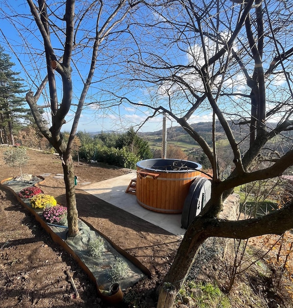 A hot tub in a garden with a view of the landscape.