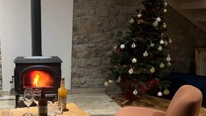 Een gezellige kamer met een houtkachel, een kerstboom en een comfortabele fauteuil.